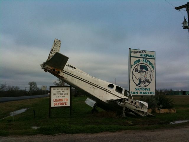A photo of a wrecked plane with the saying, 'There's no such thing as a perfectly good airplane' at a skydiving business in Texas.