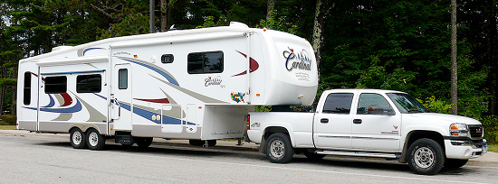 A fifth wheel trailer being pulled by a pickup truck.